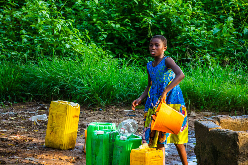 Fillette en robe bleue portant une bassine d'eau en Côte d'Ivoire, photo de Ka.O