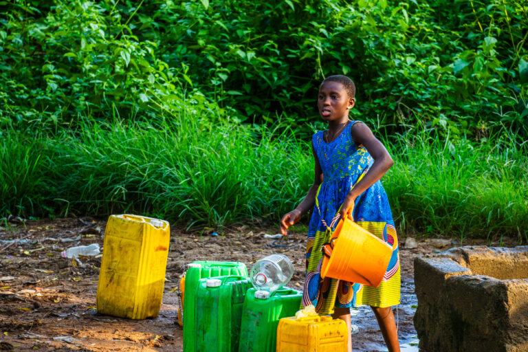 Fillette en robe bleue portant une bassine d'eau en Côte d'Ivoire, photo de Ka.O