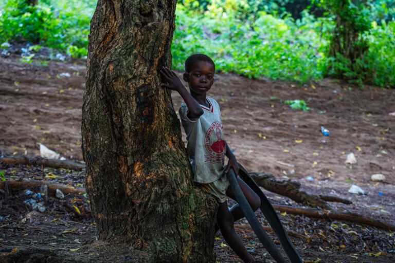 Jeune garçon adossé à un tronc d'arbre, portrait documentaire à Abidjan par Ka.O