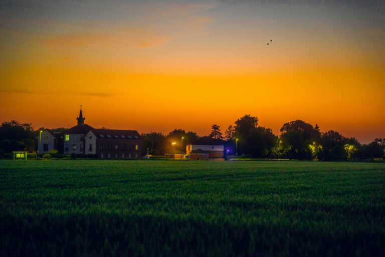 Clocher et village en silhouette sous un ciel orange au crépuscule, photo de Ka.O