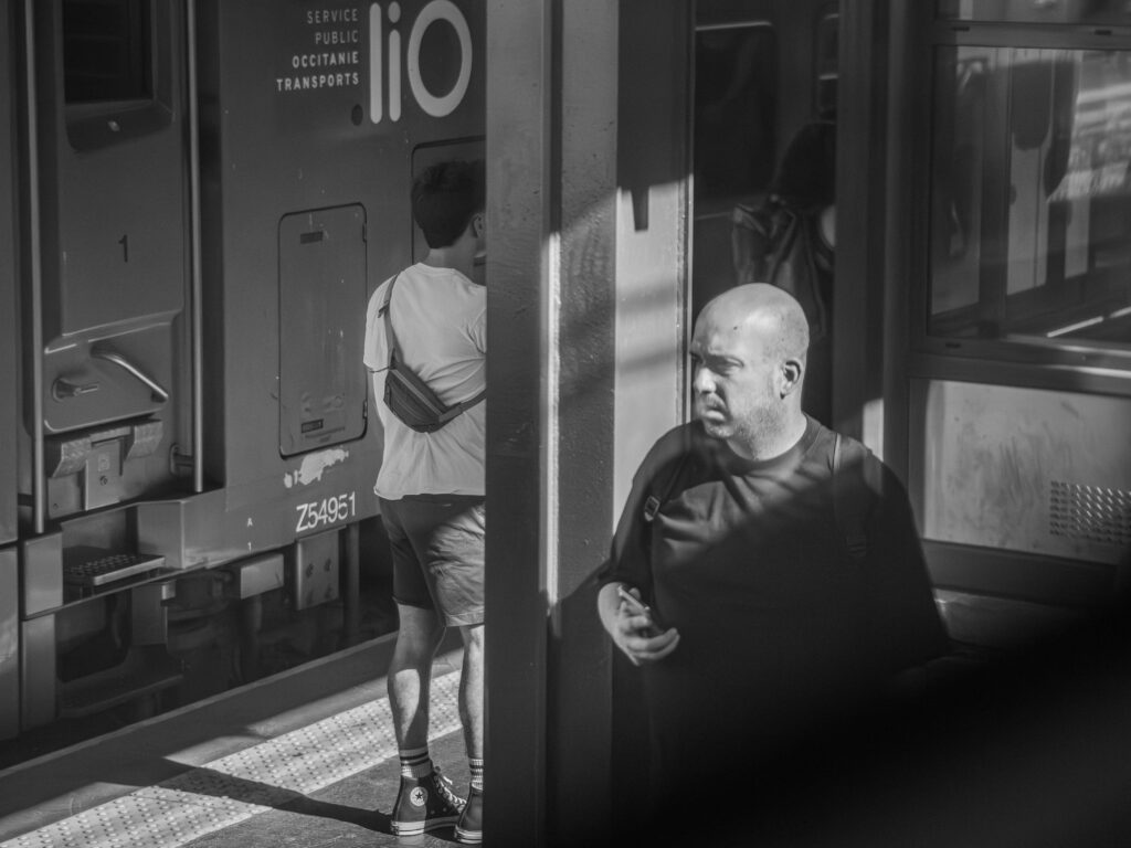 Homme seul dans un train, lumière dure et reflets, street photographie de Ka.O