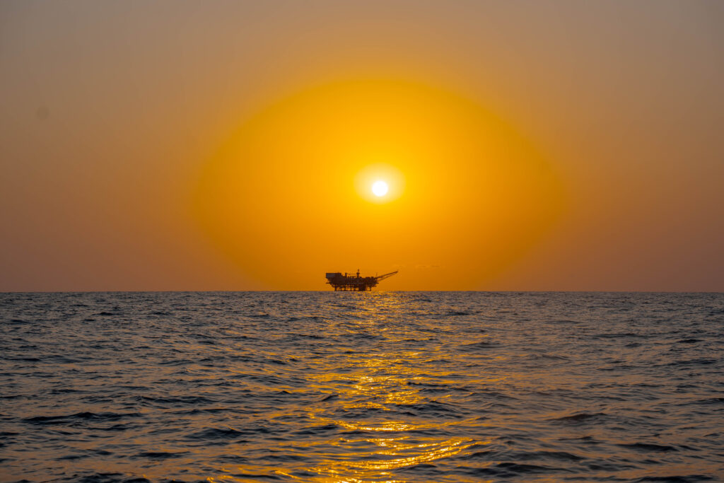 Coucher de soleil doré sur la mer avec une plateforme en silhouette, photo de Ka.O