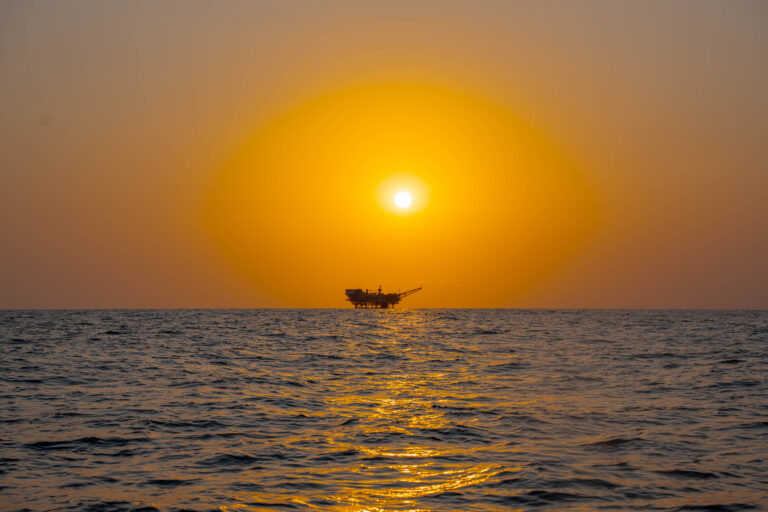 Coucher de soleil doré sur la mer avec une plateforme en silhouette, photo de Ka.O
